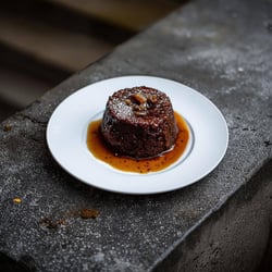 sticky date pudding on a dark concrete bench with the plate as the liught hero